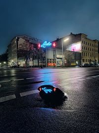 Lido club neon sign reflecting in puddle on street at night