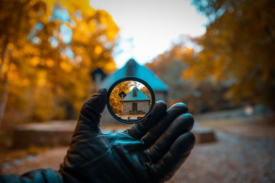 House seen through circle shaped glass held by hand