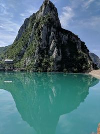 Scenic view of sea by mountain against sky