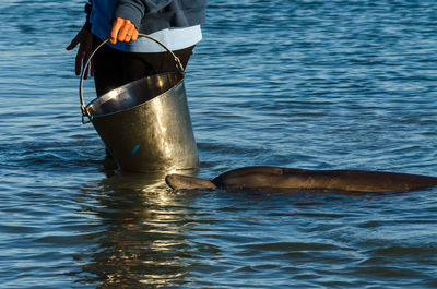 Midsection of woman with bucket standing in sea