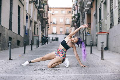 Full length of woman with dyed hair dancing on street