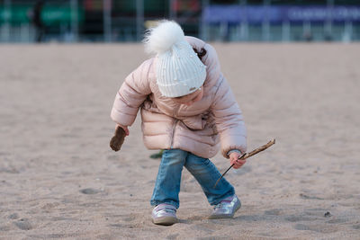 Little girl is playing on an empty beach on a cold day