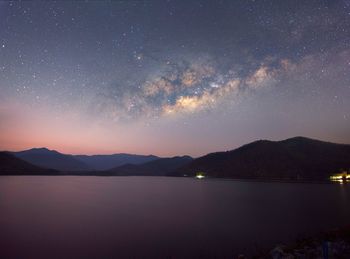 Scenic view of lake and mountains against sky at night