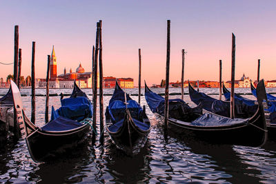 Boats moored in canal at sunset