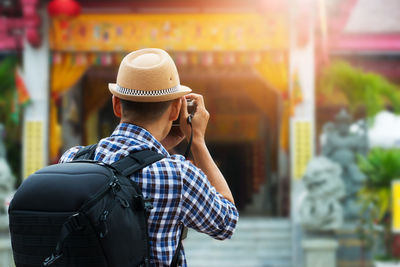 Rear view of man photographing temple through camera