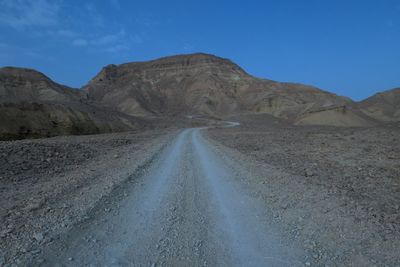 Dirt road in desert against sky