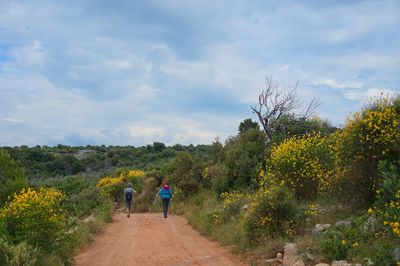 Two senior women walking down the road with mediterranean flora around them