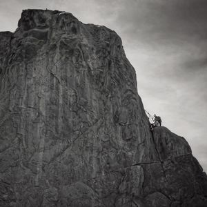 Low angle view of man standing on rock formation against sky