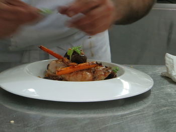 Close-up of man preparing food in plate