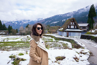 Portrait of woman standing in snow against mountains