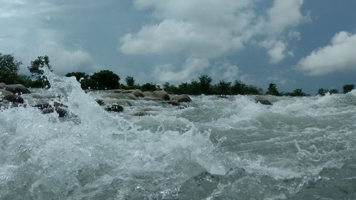 Waves splashing on shore against sky