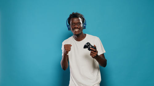 Man wearing headphones while standing against blue background
