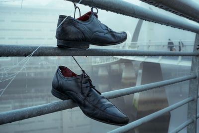 Close-up of shoes hanging on city bridge