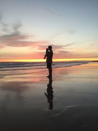 Silhouette man standing on beach against sky during sunset