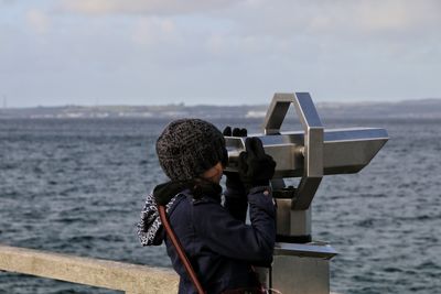 Rear view of girl looking through binoculars on the sea