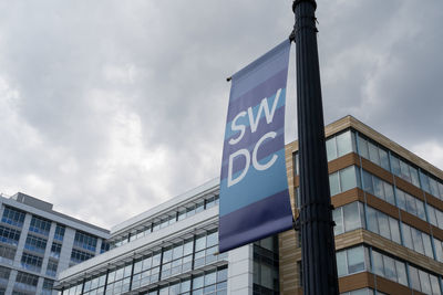 Low angle view of sign by building against sky