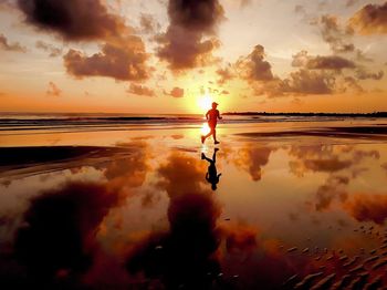 Man standing on beach against sky during sunset