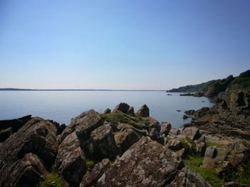 Scenic view of sea and cliff against clear blue sky