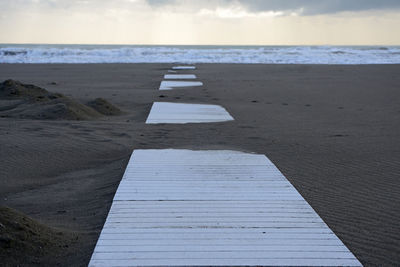 Boardwalk on beach against sky