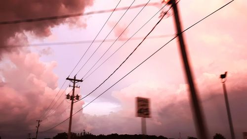 Low angle view of electricity pylon against dramatic sky