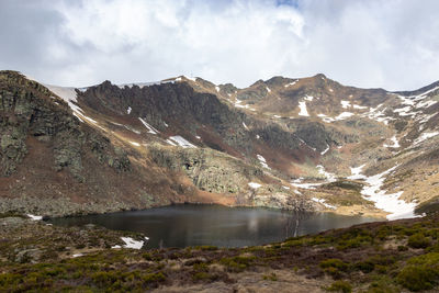 Scenic view of lake by mountains against sky