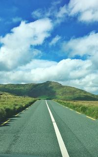 Empty road on field against cloudy sky