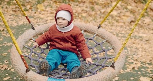 Portrait of boy sitting on swing at playground