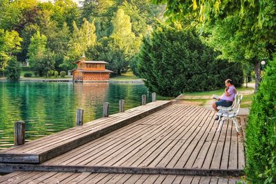 Woman sitting on wooden pier over lake