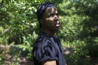 Young man standing against trees