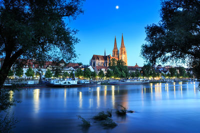 Scenic view of river by building against blue sky