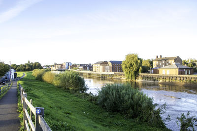 Buildings by river against sky in city