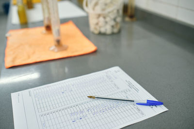 High angle of scientific report of experiment placed on table with pen in contemporary chemical laboratory
