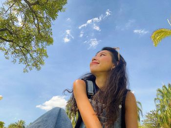 Young woman looking away against sky