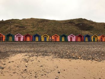 Beach huts by buildings against sky