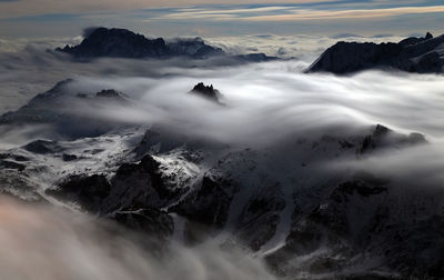 Scenic view of clouds covering snowcapped mountains