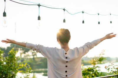 Low angle view of man with arms raised standing against sky