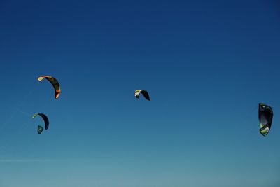 Low angle view of paragliding against clear blue sky