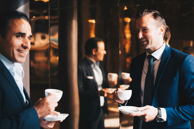 Smiling mature male business colleagues drinking coffee at cafe