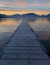 Pier over lake against sky during sunset