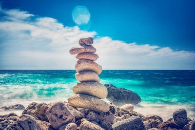 Stack of pebbles on beach against sky