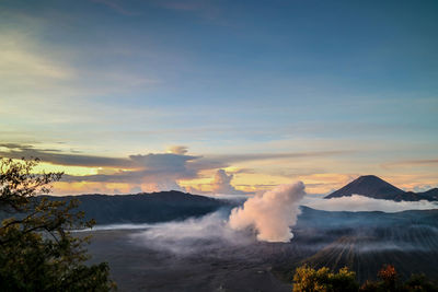 Smoke emitting from volcanic bromo mountain against sky during sunset 