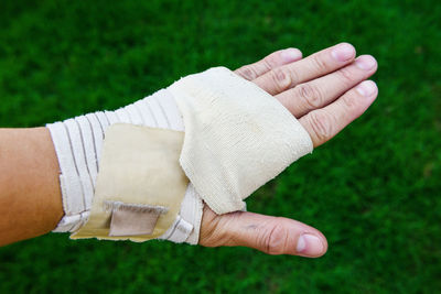 Cropped image of person with broken hand over grassy field