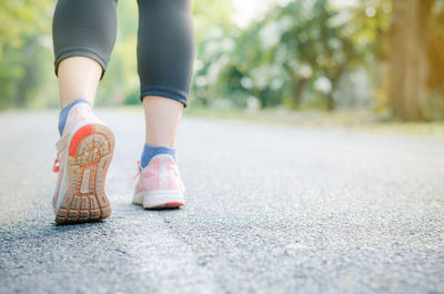 Low section of woman walking on road