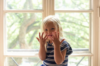 Portrait of smiling girl against window at home