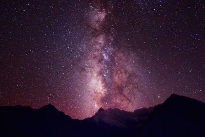 Low angle view of silhouette mountain against star field