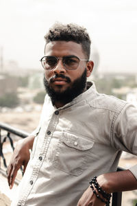 Portrait of young man wearing sunglasses against lake