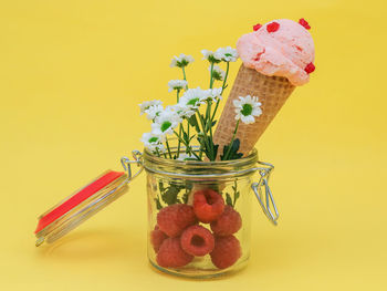 Raspberry ice cream with fresh berries and flowers in a jar.