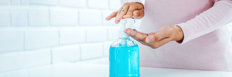 Close-up of woman holding hands against white wall