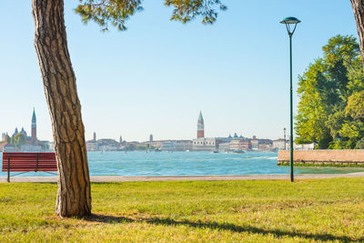 Beautiful park with green lawn, bench an view to city. venice, italy