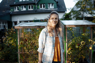 Smiling woman with blond hair standing at backyard